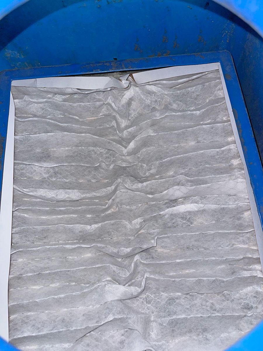 Close-up of a dirty air filter on a blue bin