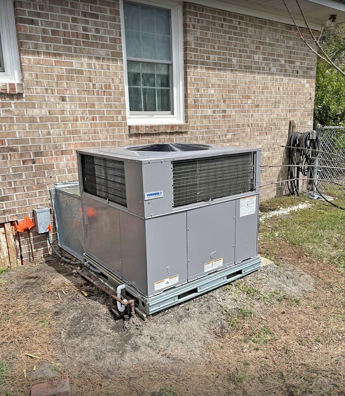 Package unit installed beside a brick house on fresh dirt