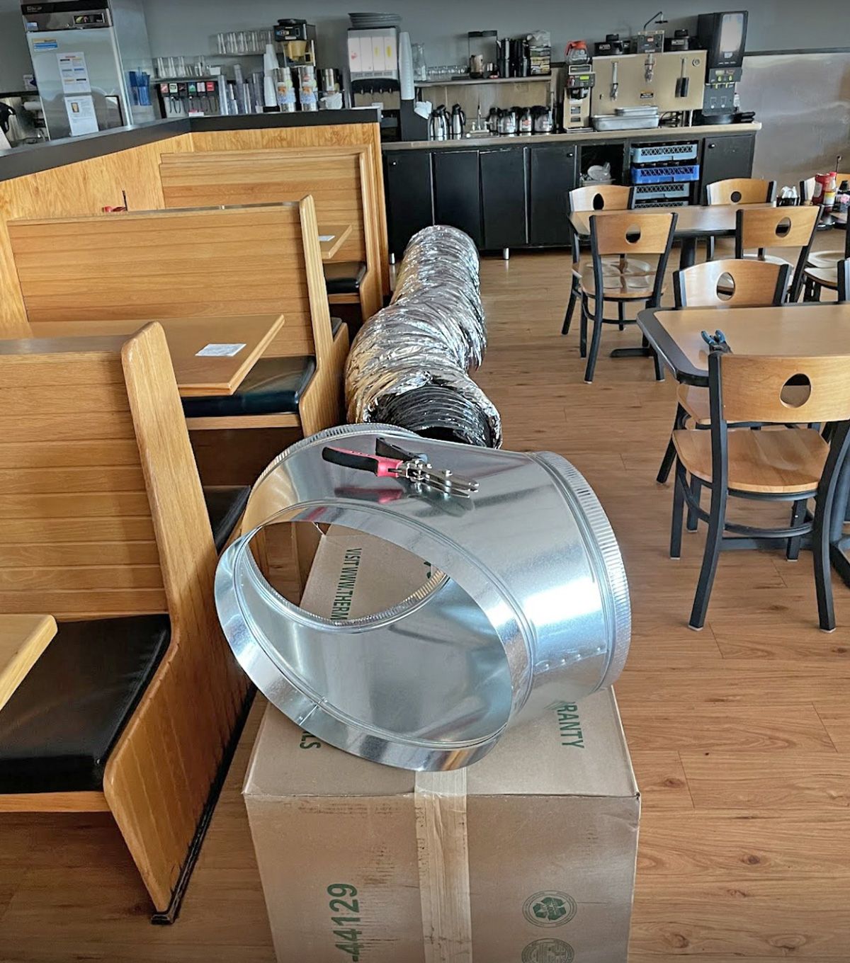 Restaurant dining room with flex duct and a new metal fitting staged on the box (commercial job)