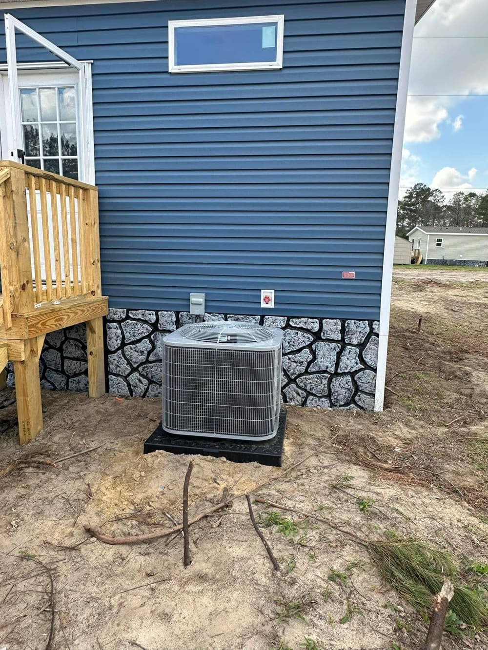 New condenser on a black pad beside a blue house