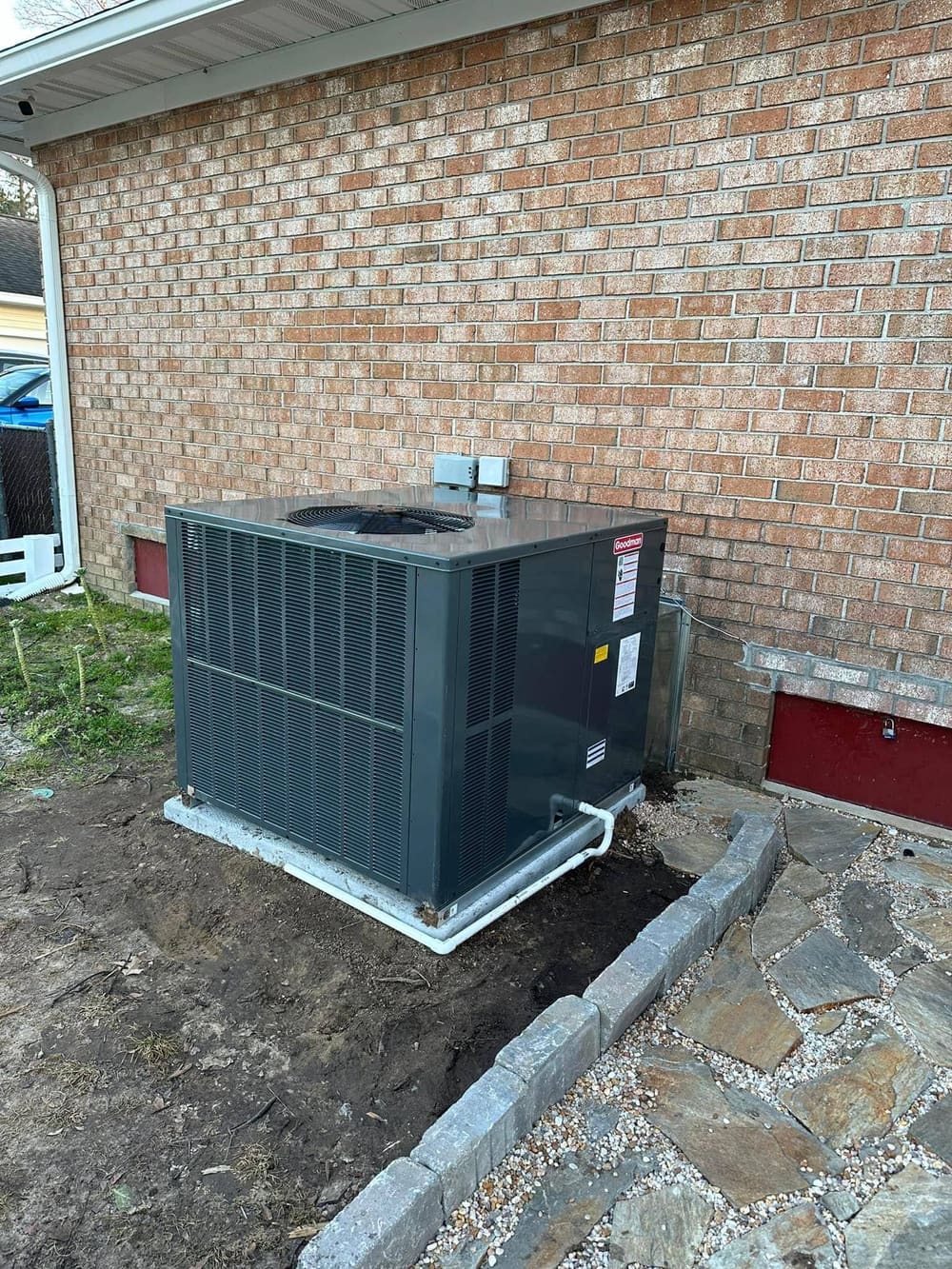 New condenser set on a pad beside a brick house