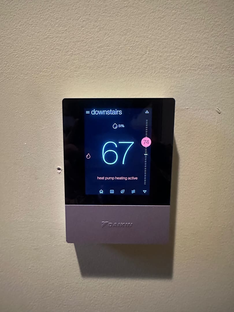Daikin thermostat on a wall showing heat pump heating active