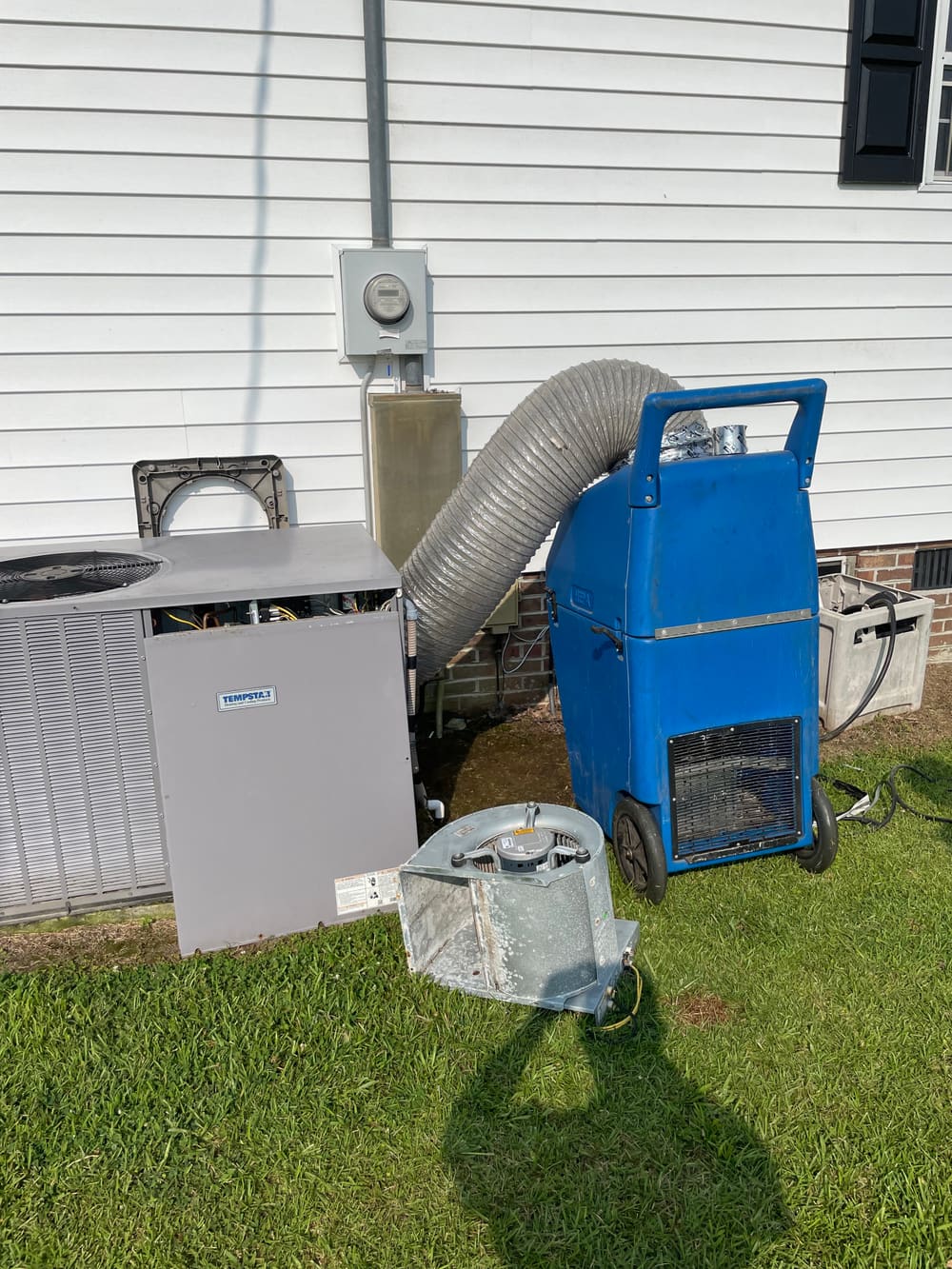 Duct cleaning machine and hose set up by a house beside the air handler cabinet