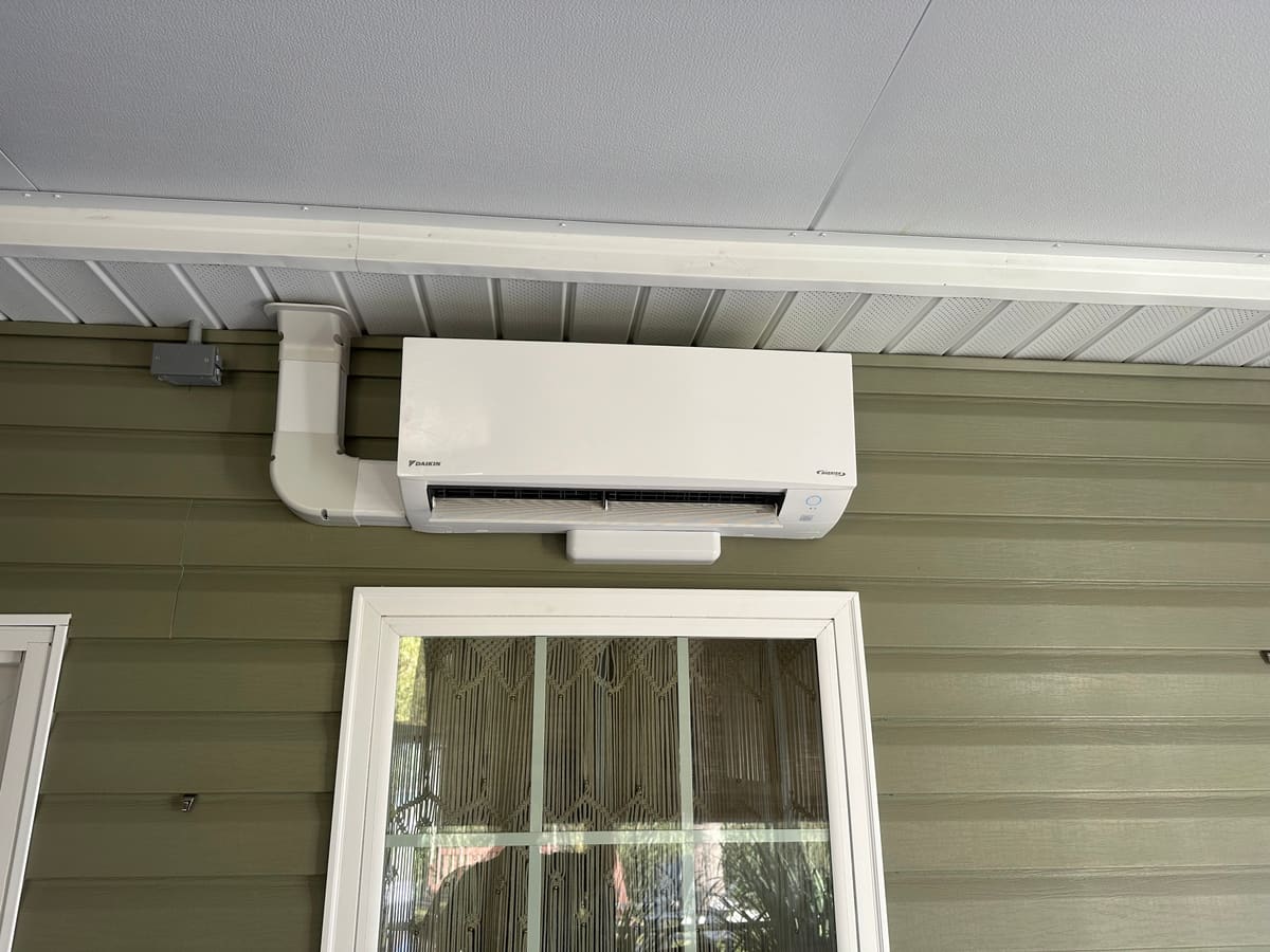 Mini-split head mounted on a wall beside a window