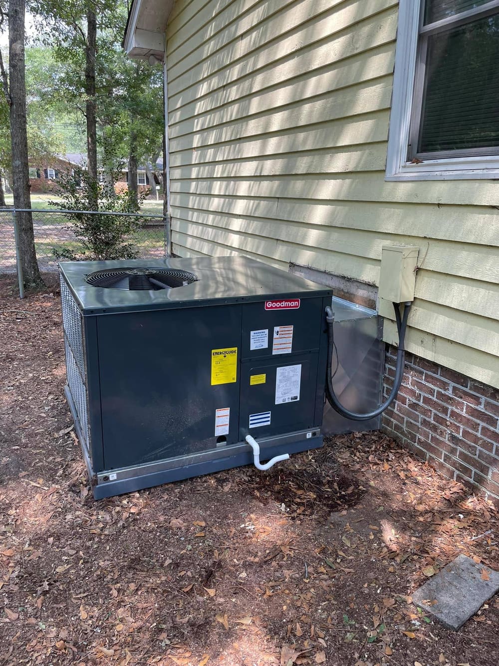 Package unit on a pad beside a brick house