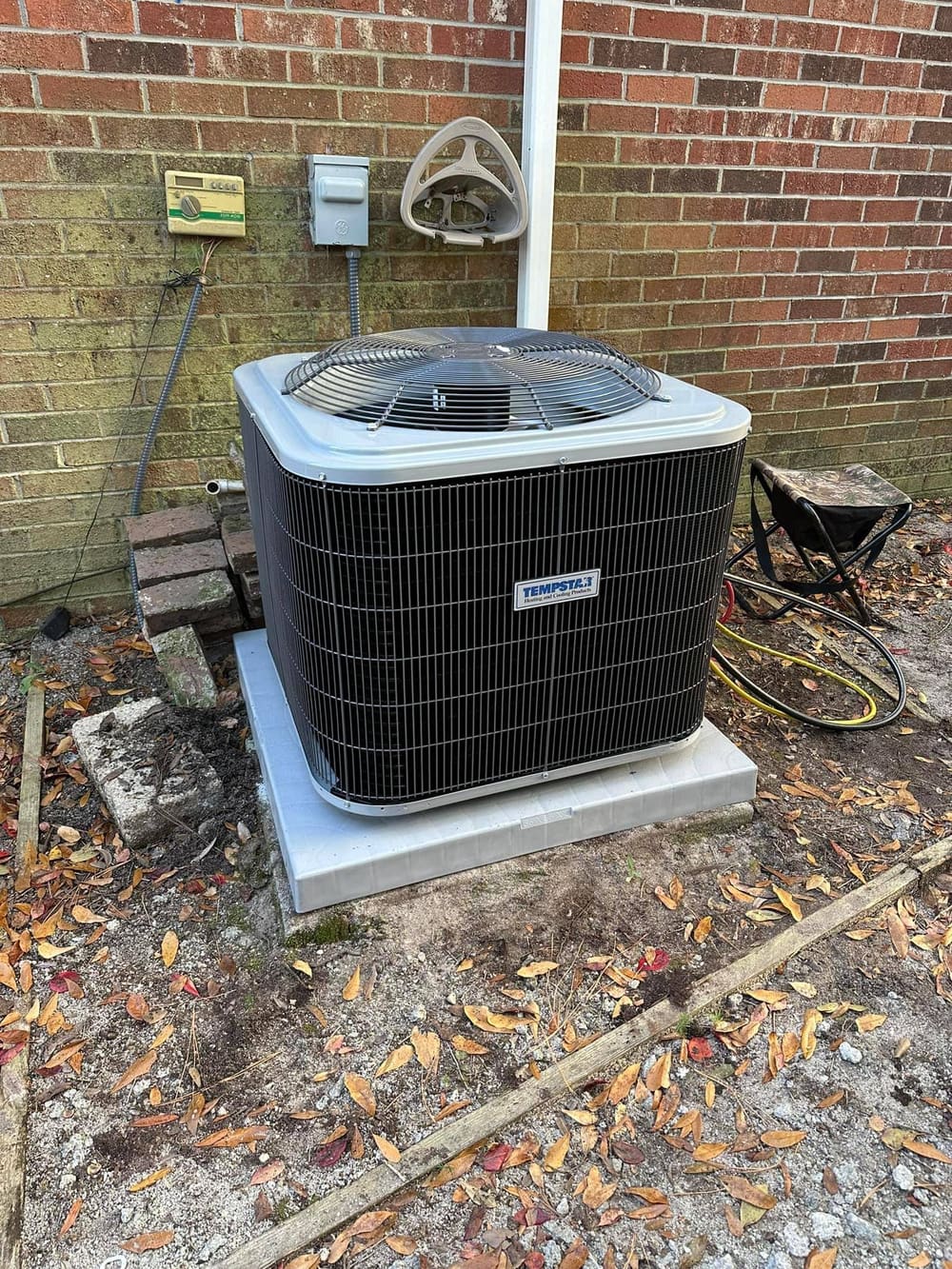 New outdoor condenser on a pad against a brick wall